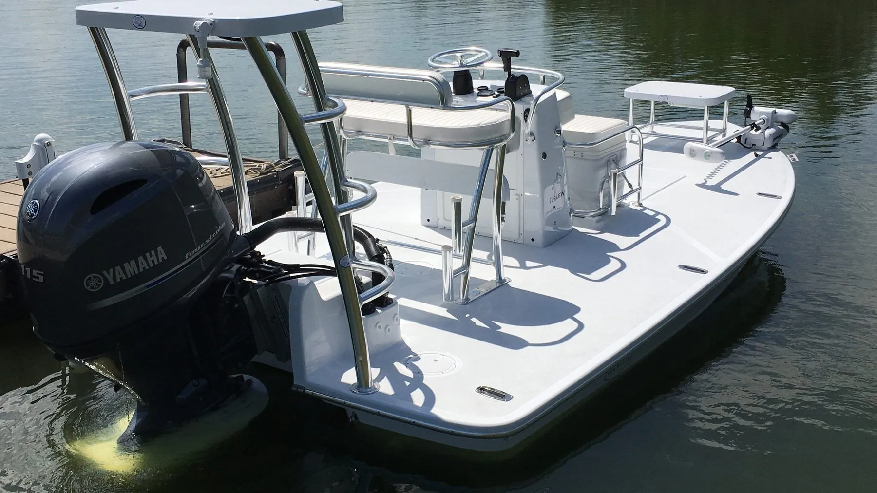 A shallow-draft flats skiff tied at a dock, casting deck forward